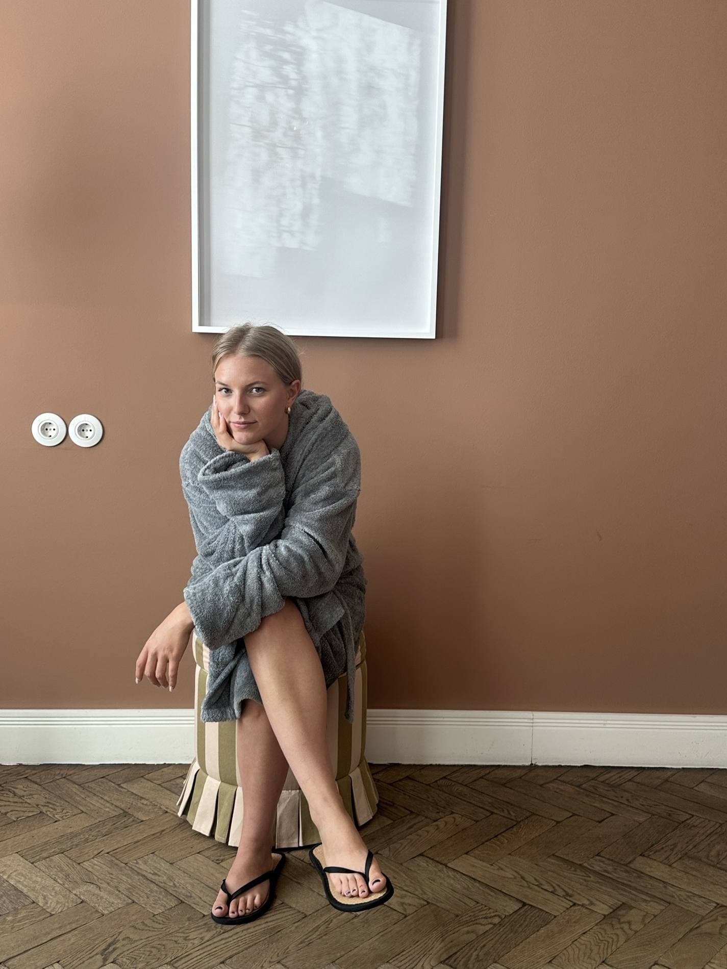 Jill sitzt in eine Strickjacke gewickelt auf einem Hocker